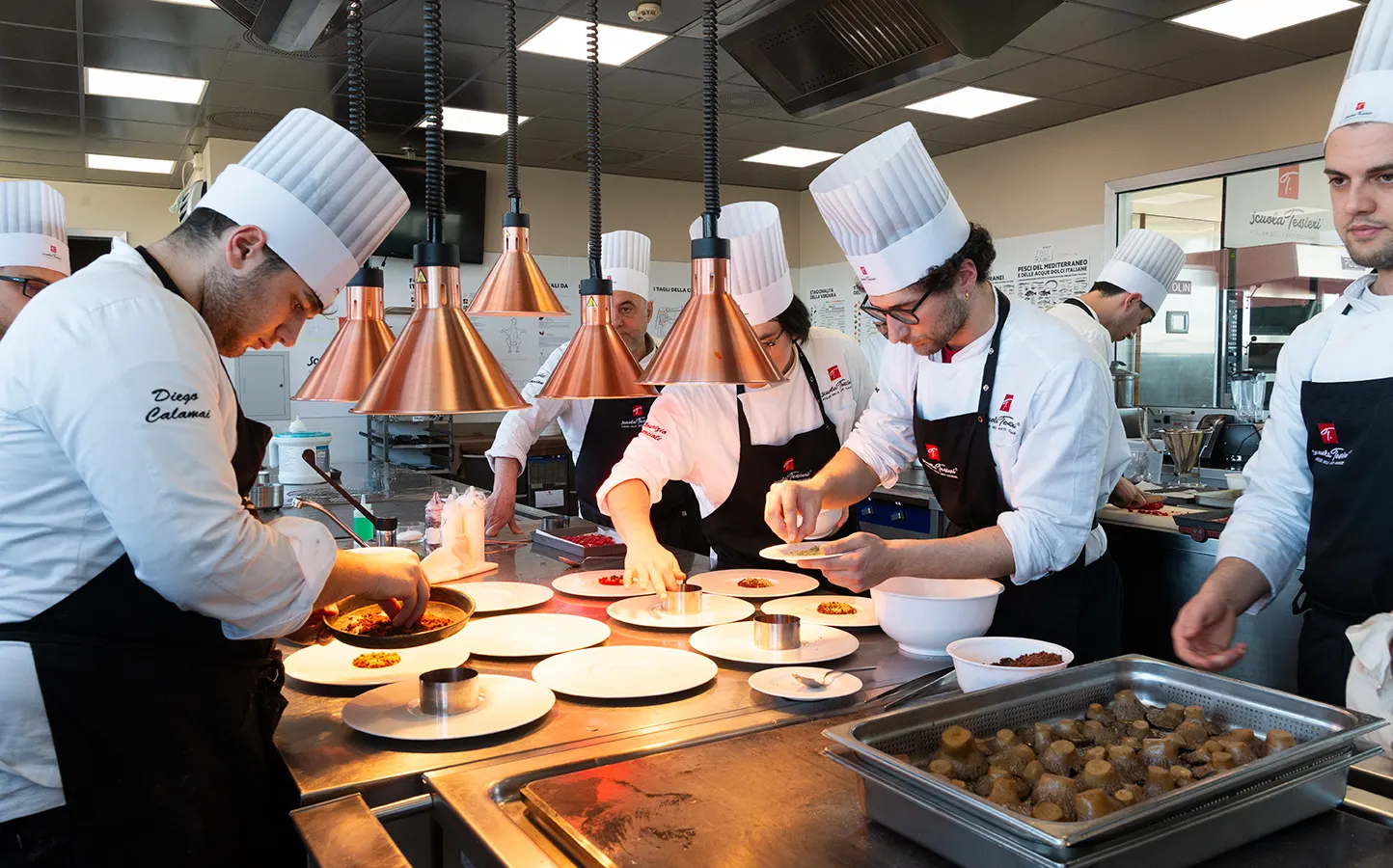 Studenti di Scuola Tessieri impiattano sotto le lampade nel laboratorio di cucina